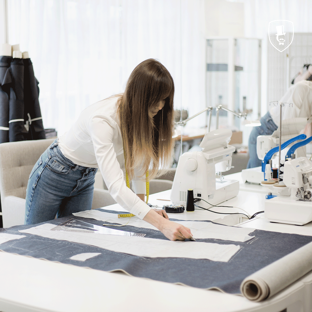 Woman working with fabric on a table in a tailoring workshop.