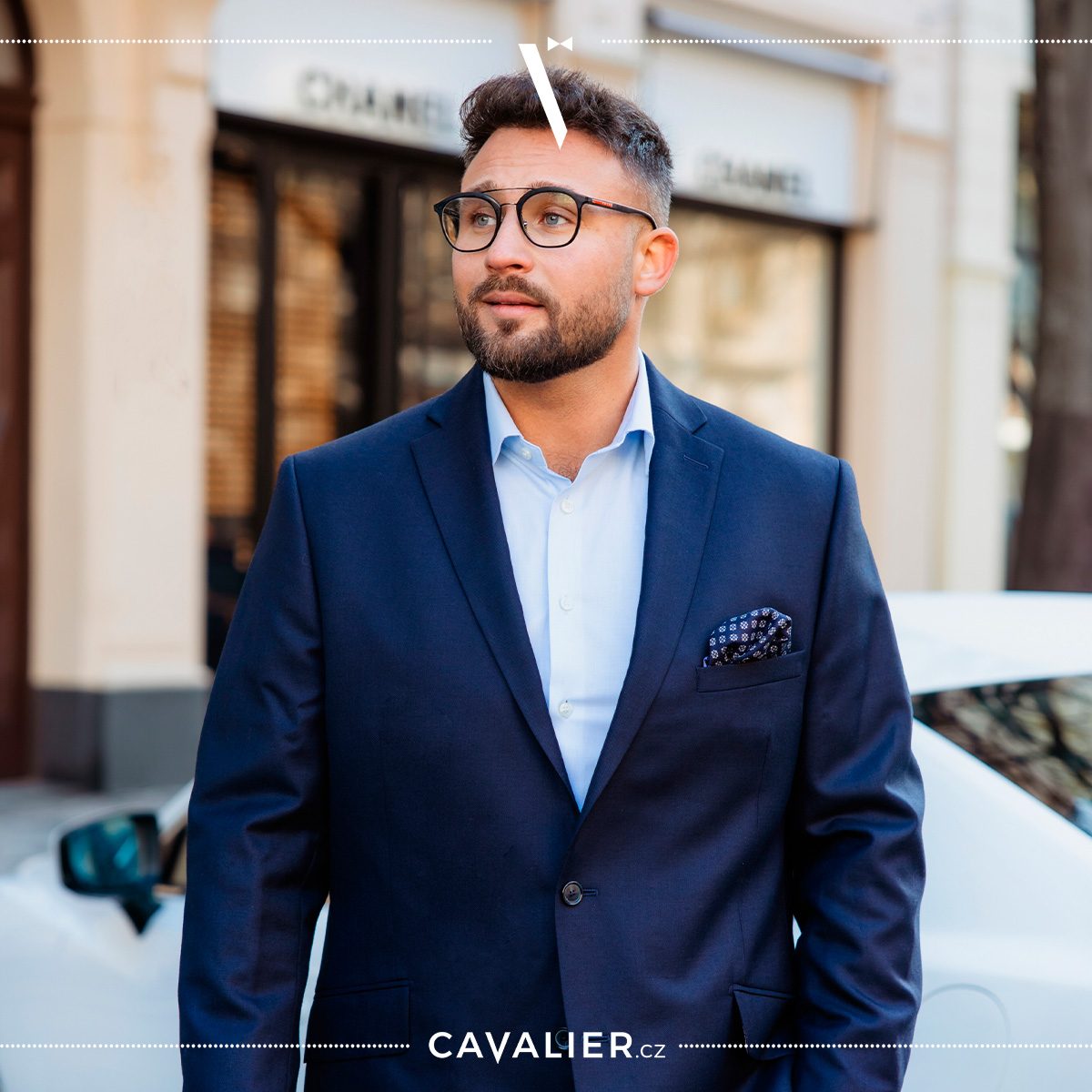 Man in a navy blazer and light blue shirt with a dark pocket square.