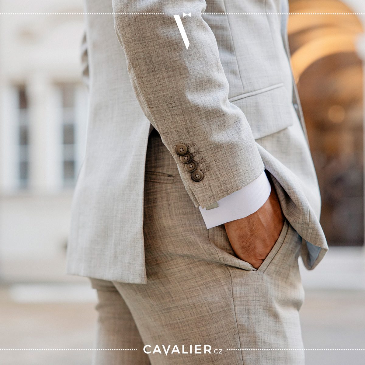Light grey suit sleeve with four buttons beside a white shirt cuff.
