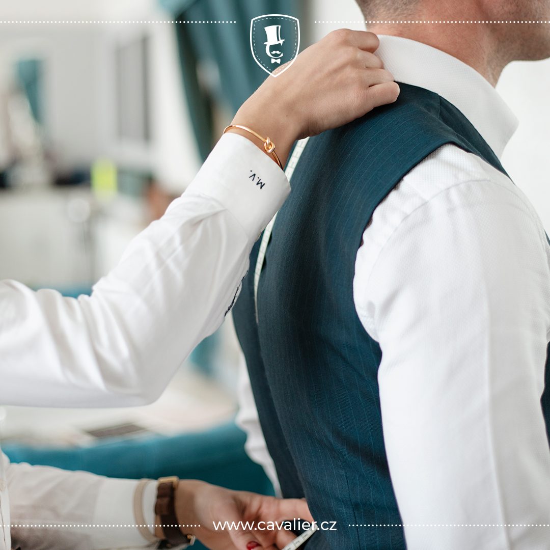 A waistcoat is adjusted near the collar during a fitting.
