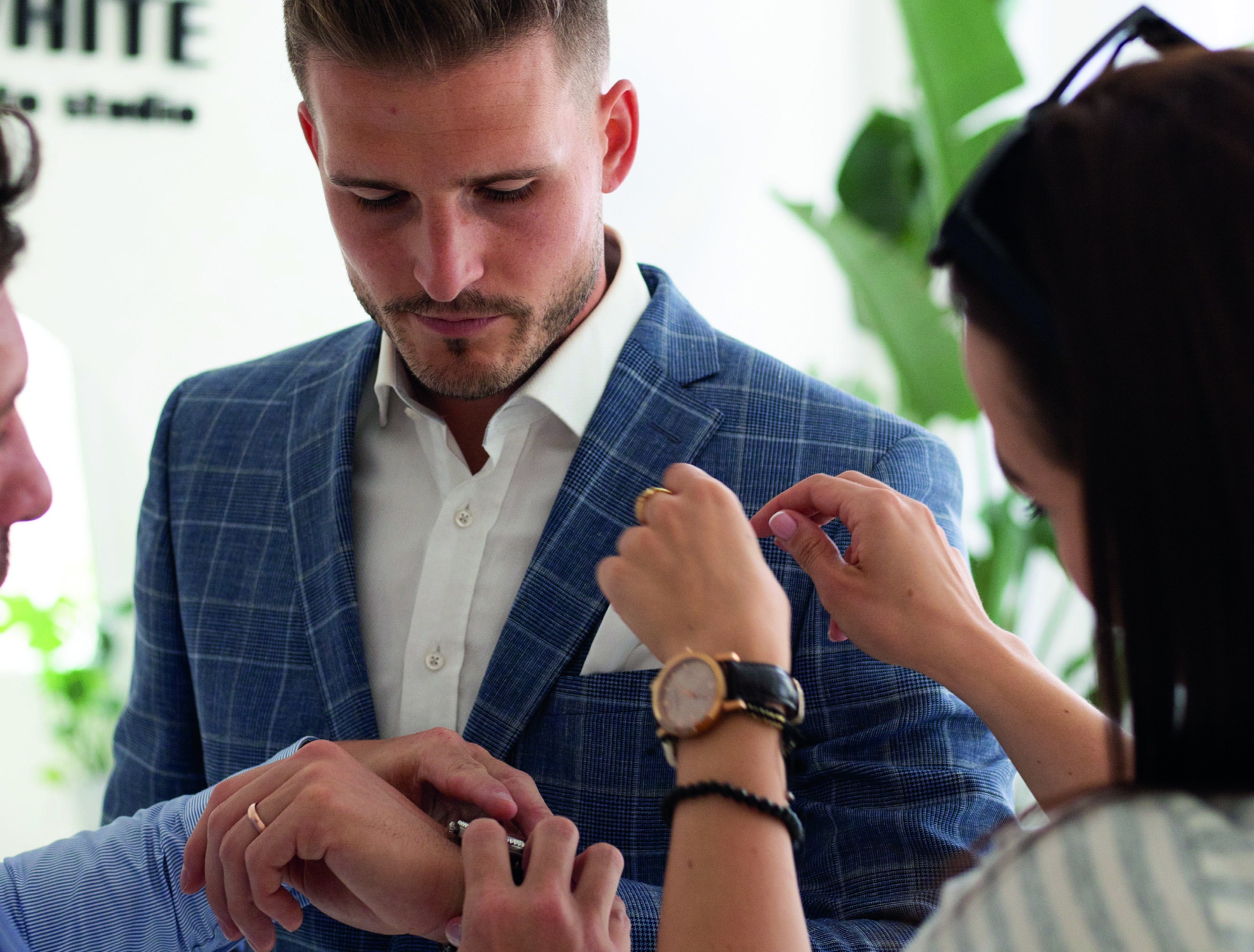 Tailor adjusting the lapel of a blue checked jacket during a consultation