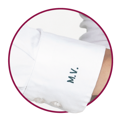 White blouse cuff with embroidered initials.